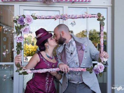 Happy spouses in victorian age fashion, kissing behind a pink rose frame