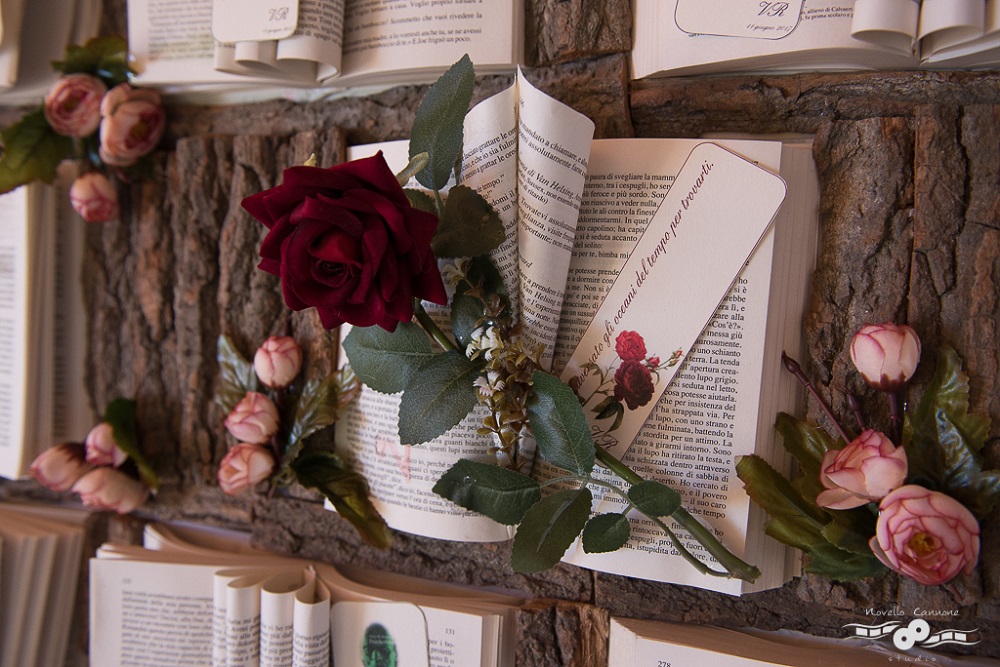 Close up of a Tableau du Marriage made with victorian literature, with a red rose on top, on a sheet of tree bark