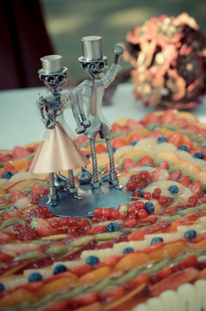 A Cake Topper made in metal, with the bride and groom imprisoned, over a fruit cake