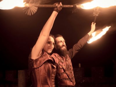 Smiling bride and groom in steampunk style clothing, posing with burning fire show equipment