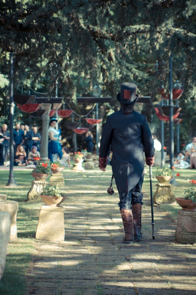 A steampunk dressed groom waking towards a garden wedding ceremony