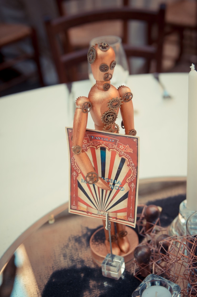 Victorian Circus inspired bronze puppet, with gears and a table sign under the arm