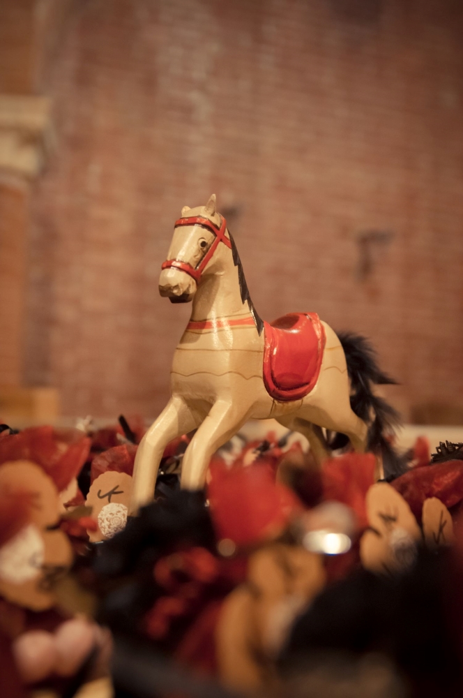 A wooden horse on top of small black and red bags of party favors in a castle courtyard