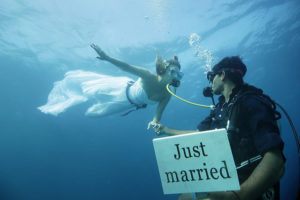 Elopement - Scuba spouses, the groom holds a 
