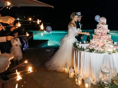 Sposi nella loro location perfetta, che tagliano la torta di fronte alla piscina con gli ospiti con le stelle scintillanti