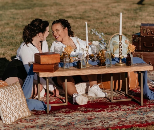 Two women in front of a beautifully decored table, with candles and wooden boxes - Micro-weddings